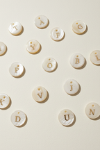 Parelmoer letter charms crème achtergrond